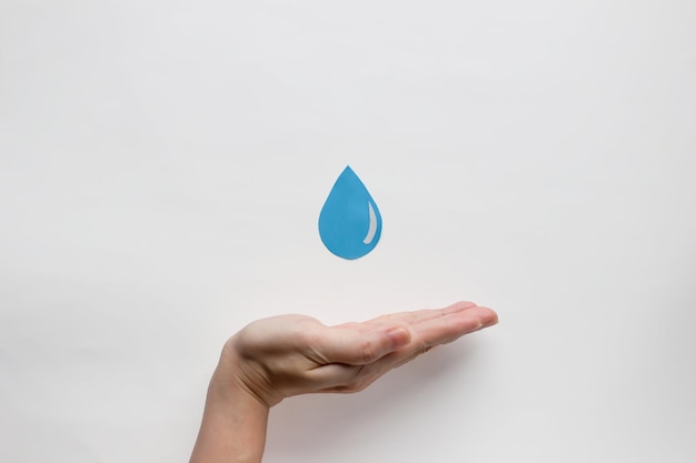 Foto la forma della goccia d'acqua di carta è tenuta dalla mano della donna per risparmiare acqua per incoraggiare una giornata mondiale dell'acqua