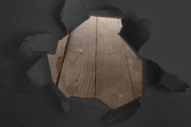 Paper with a hole torn in the middle with wooden table background