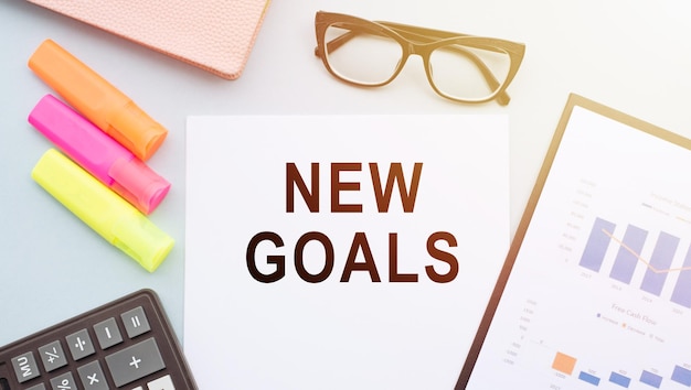 Paper with new goals text on office table Top view flat lay