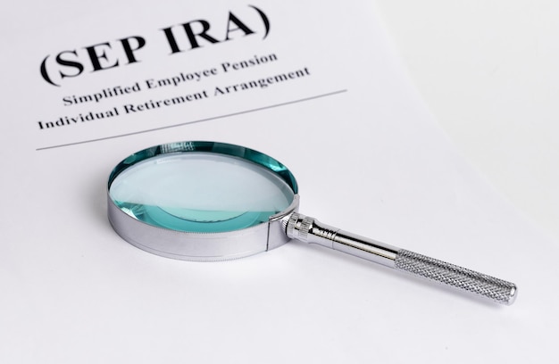 Paper with sep ira words and magnifying glass simplified\
employee pension individual retirement arrangement analysis and\
planning of contributions business and finance concept