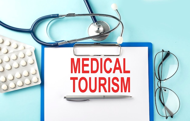 Paper with text MEDICAL TOURISM on a blue background with stethoscope and pills