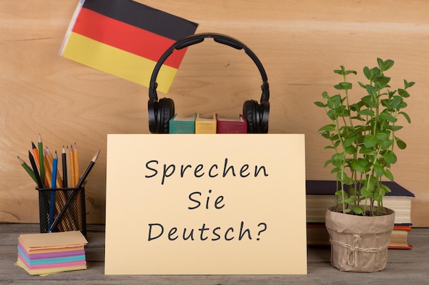 독일 책 헤드폰 연필의 텍스트 sprechen sie deutsch 플래그가 있는 종이