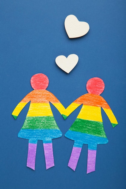 Paper women cut from paper and painted in LGBT colors with white hearts Concept of LGBT on dark blue Space for text