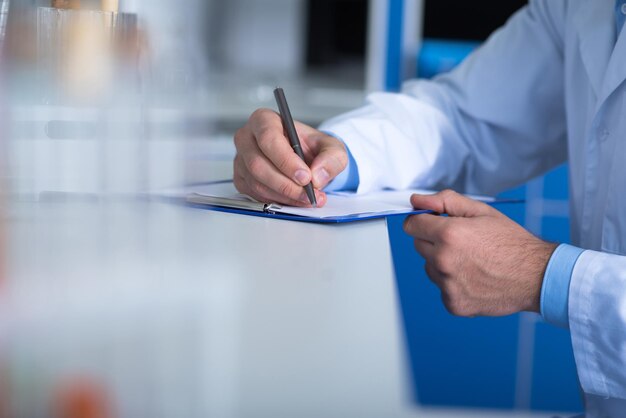 Paper work Reasonable clever smart explorer sitting in the laboratory by the table and noticing results of the research