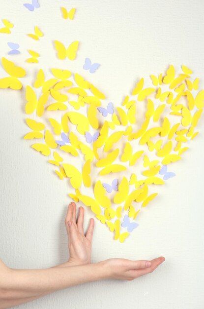 壁にハートの形の紙の黄色い蝶