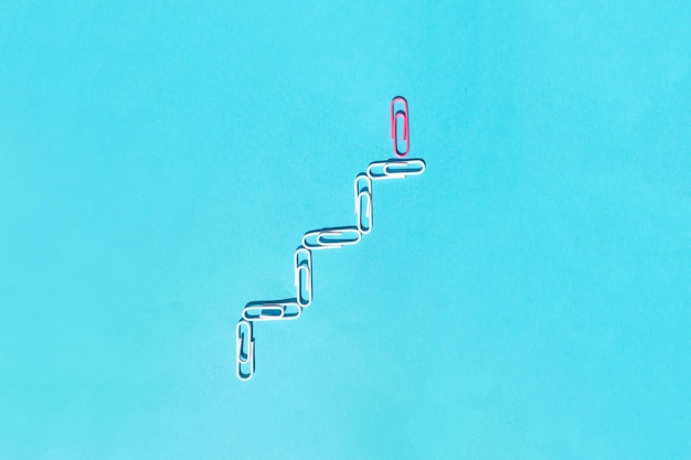 Paperclips on blue background Success growth concept