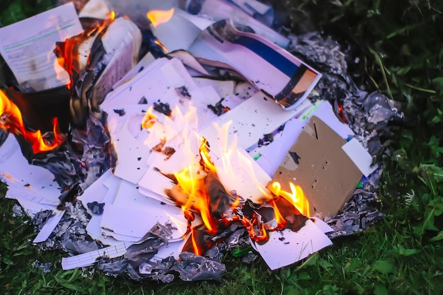 Papier branden op groen zomergras buitenshuis.