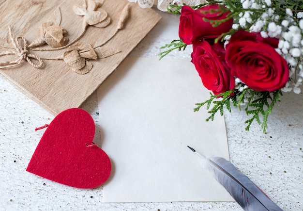 Papier en pen om liefdesboodschappen te schrijven met boek en rozen