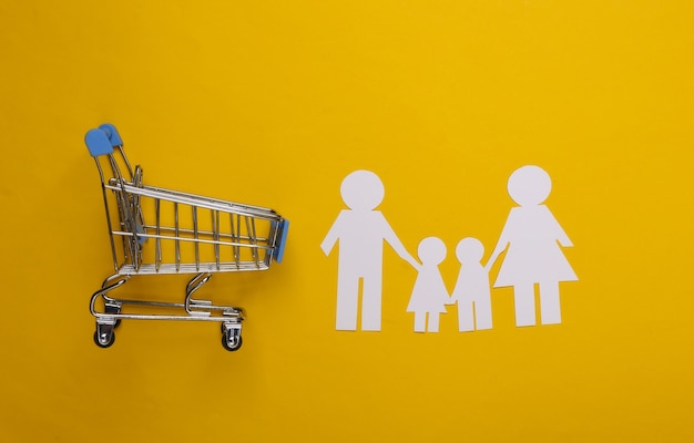 Papier familie samen en supermarkt trolley op een geel. Familie winkelen.