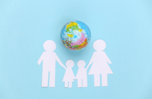 Papier familie samen met globe op blauw. Concept van ecologie, bevolking, familie, dag van de aarde. Wereld ons huis