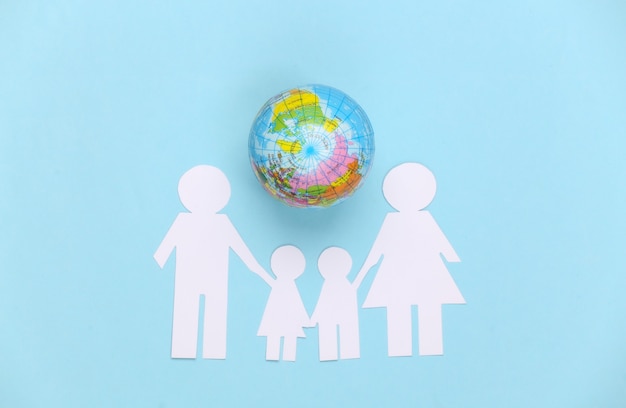 Papier familie samen met globe op blauw. concept van ecologie, bevolking, familie, dag van de aarde. wereld ons huis