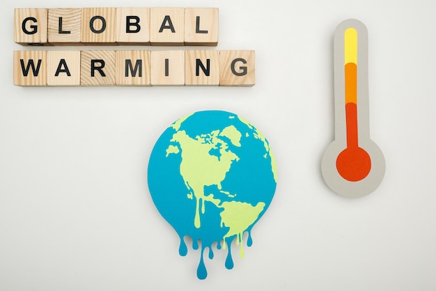 Papier gesneden smeltende aarde houten kubussen met 'global warming' letters en thermometer met hign