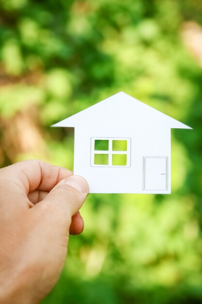 Papier huis in handen op een achtergrond van onroerend goed