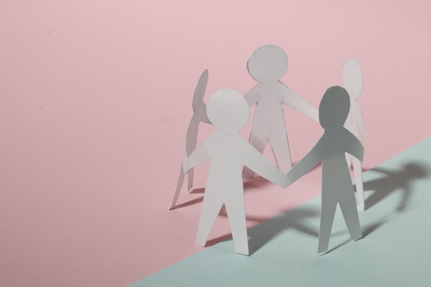 Papier knippen stijl concept van een leider en relatie met vriendschap en hand-holding van mensen in symbolische vorm op inspiratie stijl en moderne roze plakken achtergrond - 3D-rendering