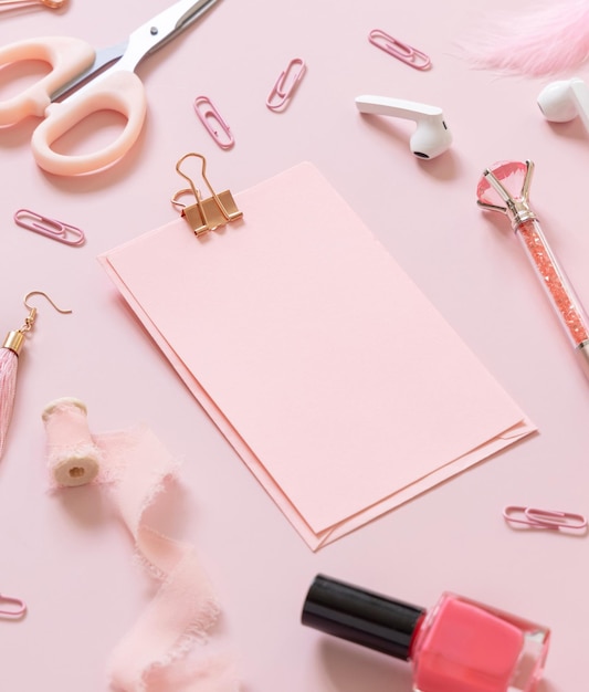 Papier met een clip en roze schoolaccessoires op pastelroze close-up leerboekmodel Girly-werkplek met schaar potloden pen paperclips oorbellen en horloge Terug naar schoolconcept