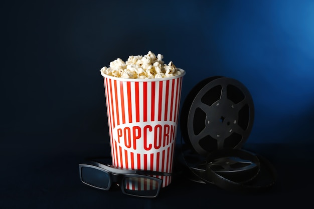 Papieren beker met lekkere popcorn, glazen en filmrol