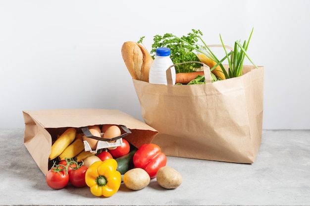 Papieren boodschappendoos vol verse biologische groenten en kruidenierswaren op grijze tafel