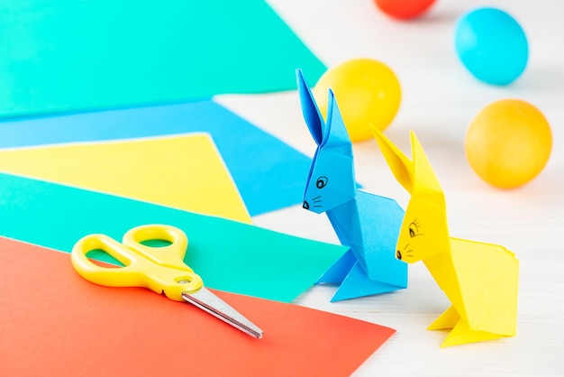 Foto papieren konijntjes met paaseieren gekleurd papier en schaar op tafel