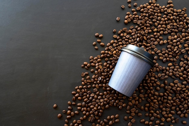 Papieren kopje koffie en bonen op zwarte houten tafel achtergrond. bovenaanzicht