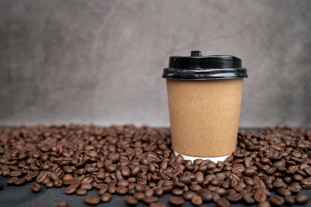 Papieren kopje koffie en bonen op zwarte houten vloer achtergrond