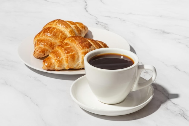 Papieren kopje koffie met croissant op witte achtergrond