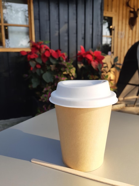 Papieren kopje verse koffie op tafel in café in ochtendzonlicht.