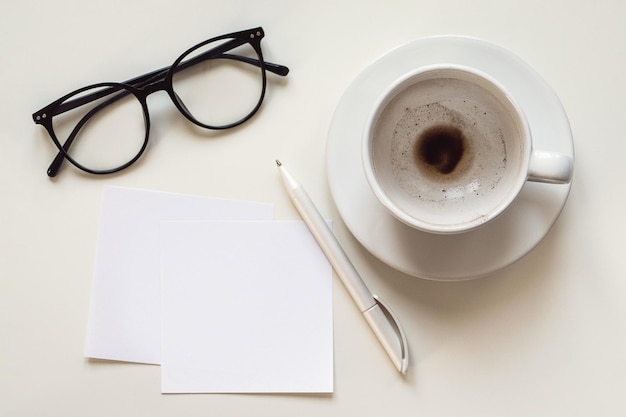 Papieren notities mockup lege ruimte lege koffiekopje brillen en pen op wit bureau overhead plat lag