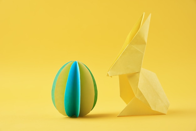 Papieren origami Pasen konijn en gekleurd ei op geel