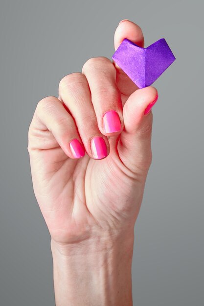 Papieren paars hart in de handpalm van de vrouw. Symbool van St. Valentijnsdag.