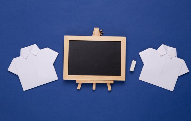 Papieren shirts en leeg krijtbord op een blauwe achtergrond Business onderwijsconcept