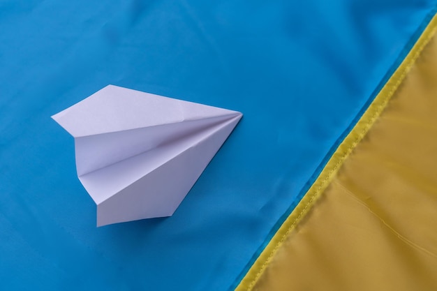 Papieren vliegtuigje op de achtergrond van de vlag van Oekraïne
