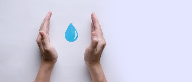 Papieren waterdruppelvorm wordt door de hand van de vrouw vastgehouden om water te besparen om aan te moedigen voor wereldwaterdag