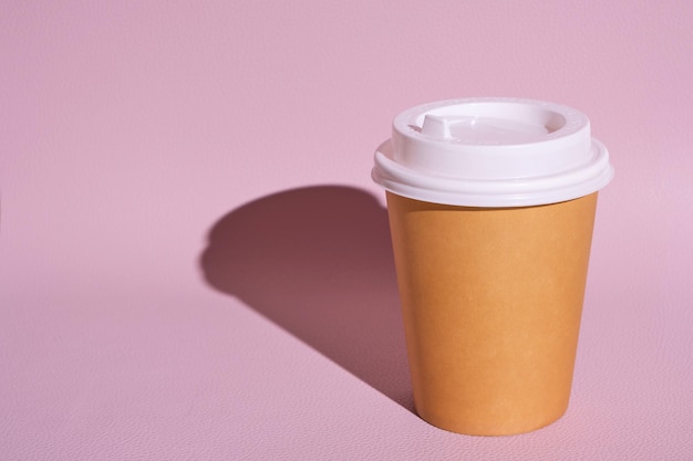 Papieren wegwerpbeker voor warme koffie en thee op roze achtergrond. Concept en trend van afhaalmaaltijden.