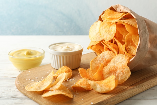 Papieren zak chips. Biersnacks, saus op scherpe raad, op witte houten, ruimte voor tekst. Detailopname