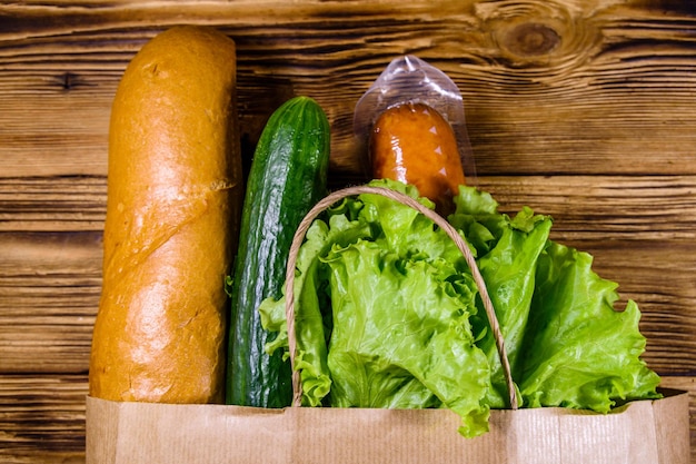 Papieren zak met ander voedsel uit de supermarkt op een houten tafel Supermarkt winkelconcept Bovenaanzicht