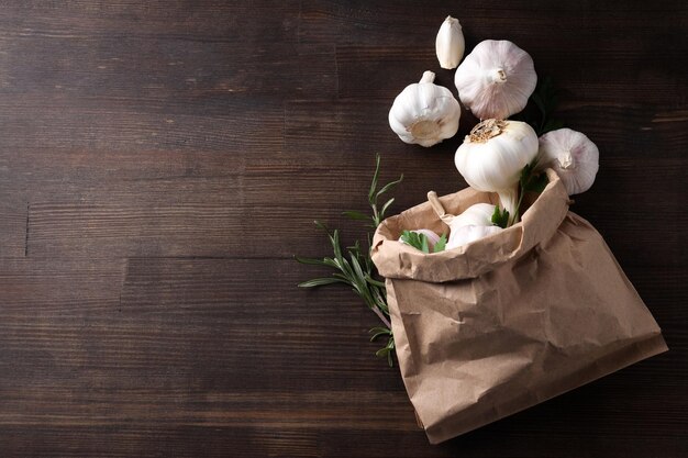 Papieren zak met knoflook peterselie en rozemarijn op houten achtergrond