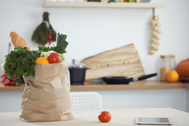 Papieren zak vol groenten op tafel in keukeninterieurs Gezonde maaltijd en vegetarisch concept