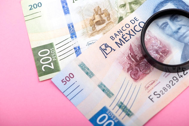 Papiergeld van Mexico en vergrootglas op roze achtergrond Mexicaanse pesos