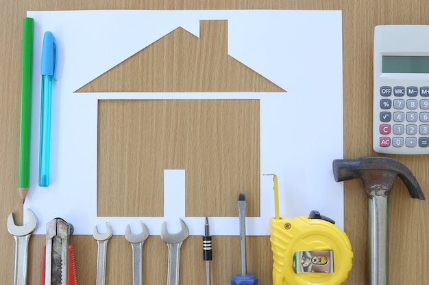 Papiervormige huis op een achtergrond van bruin hout en ambachtsman gereedschap.