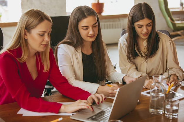 Foto papierwerk. jonge zakenvrouw in modern kantoor met team. creatieve vergadering, taken geven. vrouwen in frontoffice werken. concept van financiën, business, girl power, inclusie, diversiteit, feminisme.