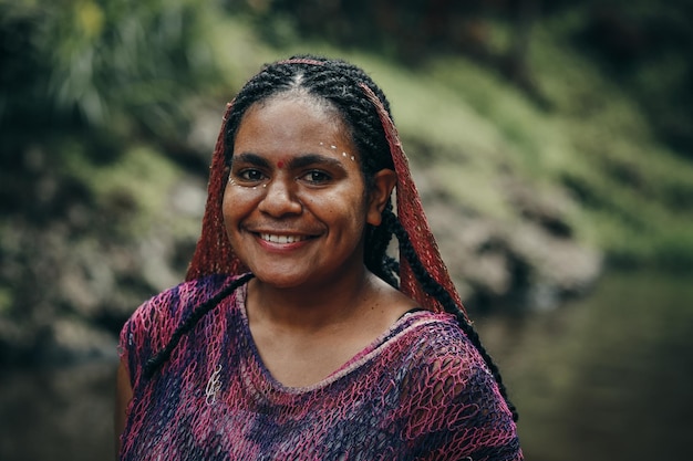 Papoea-vrouw van Dani-stam in traditionele kleding tegen rivierachtergrond