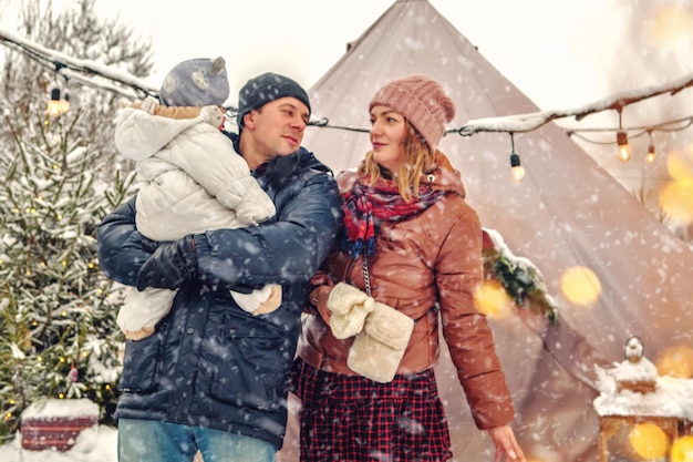 Pappa en mamma met hun zoon en dochtertje en een chocolade labrador samen op een vakantieauto met cadeautjes. De familie bereidt zich samen voor op het nieuwe jaar. Besneeuwde winter buiten.