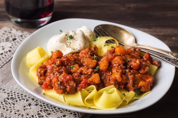 Pappardelle-pasta met vleesragout en burrata-kaas op rustieke houten achtergrond. Italiaanse keuken. Selectieve aandacht.