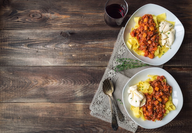 Foto pappardelle al ragù di carne con zucca e burrata su fondo di legno rustico. cucina italiana. vista dall'alto. copiare l'area dello spazio.