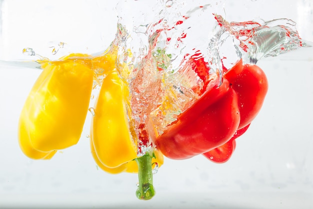 Paprika in de gele, rode, groene spatten van water, Paprika op wit