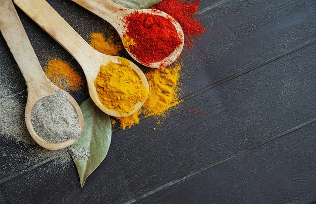 Paprika in polvere, curcuma in polvere e pepe nero su cucchiai di legno.