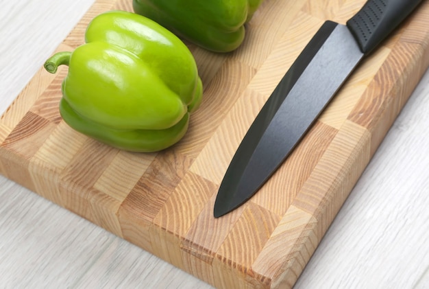 Paprika's met een keramisch mes op een houten bord. Rauw eten. Ingrediënten om te koken