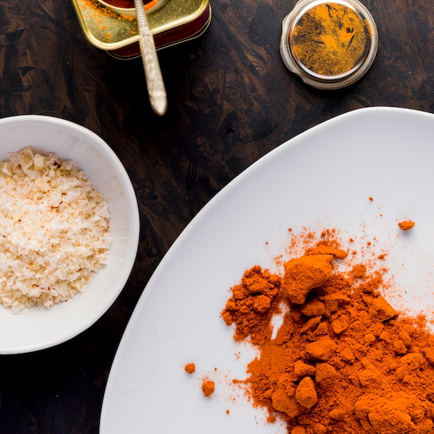 Paprika on white plate, salt and a pot on golden background