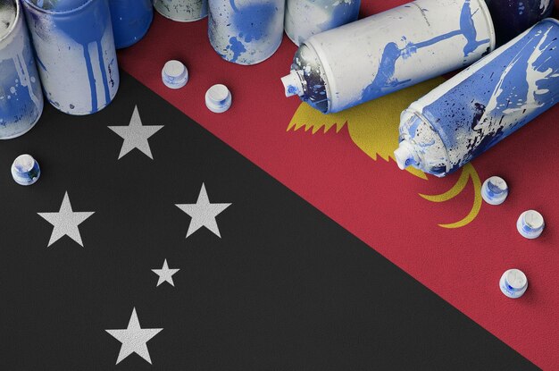 Papua new guinea flag and few used aerosol spray cans for\
graffiti painting street art culture concept