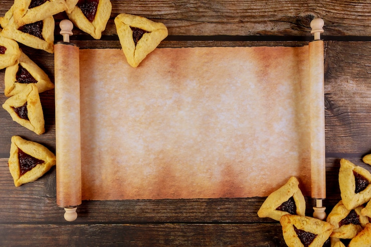 Photo papyrus roll with purim cookies on wooden background.